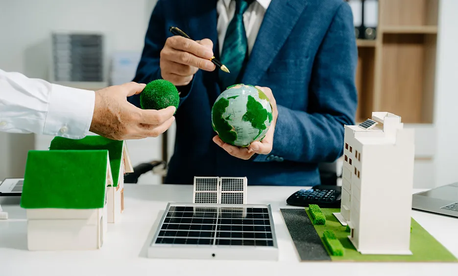 Nachhaltige Immobilien- und Energieprojekte: Geschäftsleute mit Modellen von Häusern, Solarzellen und grüner Erde – Green Solutions Gruppe
