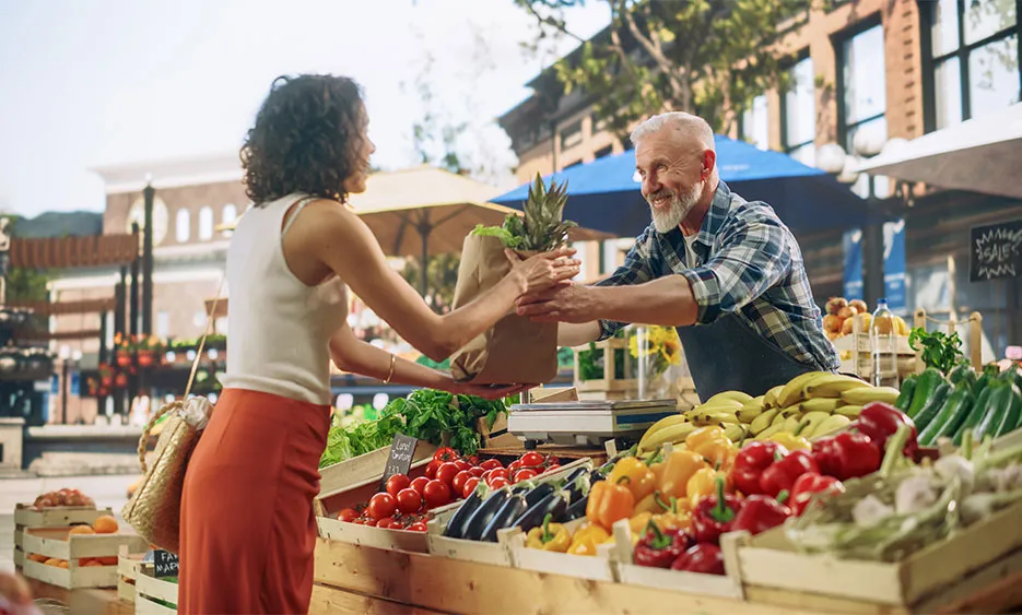 Frau kauft frisches Obst und Gemüse auf einem Marktstand, direkter Kontakt mit regionalem Händler – Green Solutions